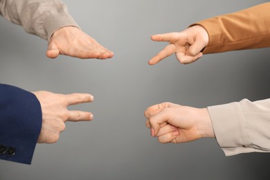 Photo of People playing rock, paper and scissors on grey background, closeup