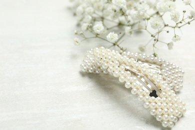 Beautiful hair clips and flowers on white table. Space for text