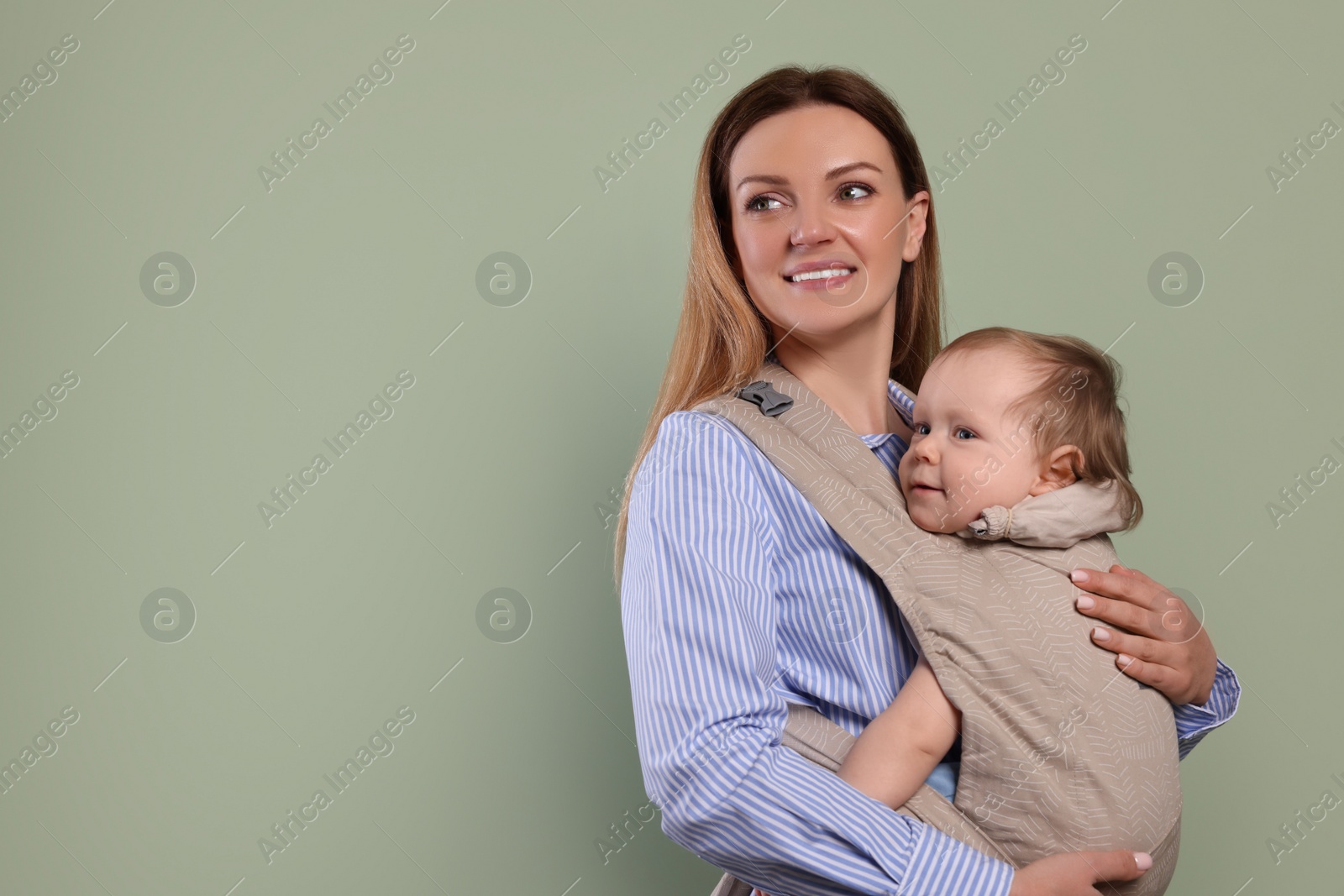 Photo of Mother holding her child in sling (baby carrier) on olive background. Space for text