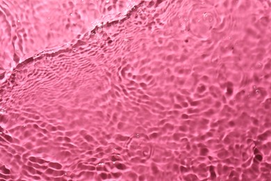 Rippled surface of clear water on bright pink background, top view