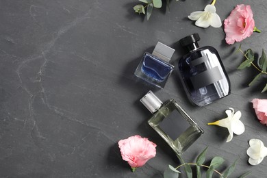 Luxury perfumes and floral decor on black table, flat lay. Space for text