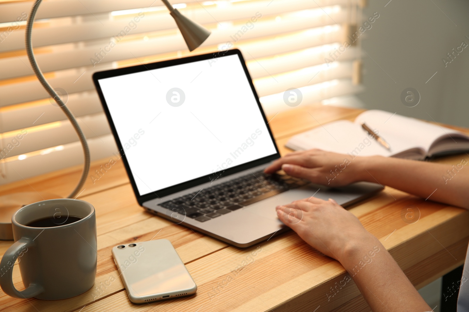 Photo of Woman working with modern laptop at wooden table, closeup. Space for design