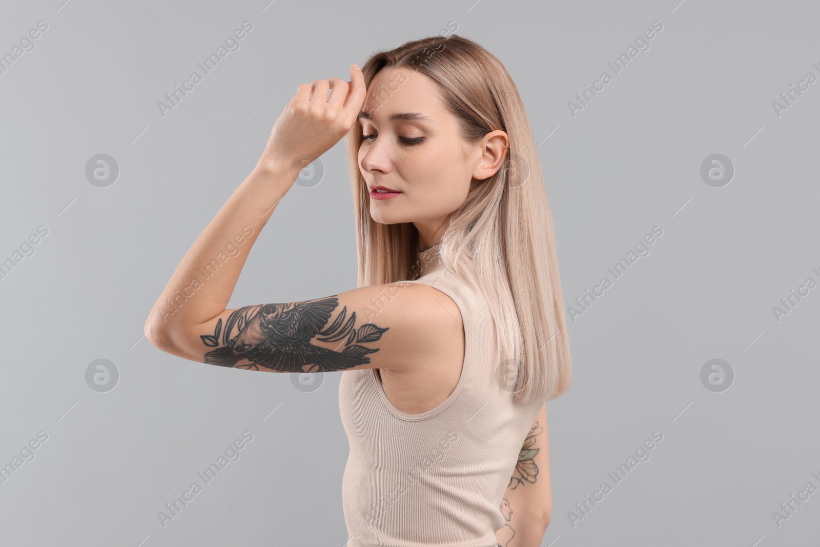 Photo of Portrait of beautiful tattooed woman on gray background