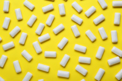 Photo of Tasty white chewing gums on yellow background, flat lay