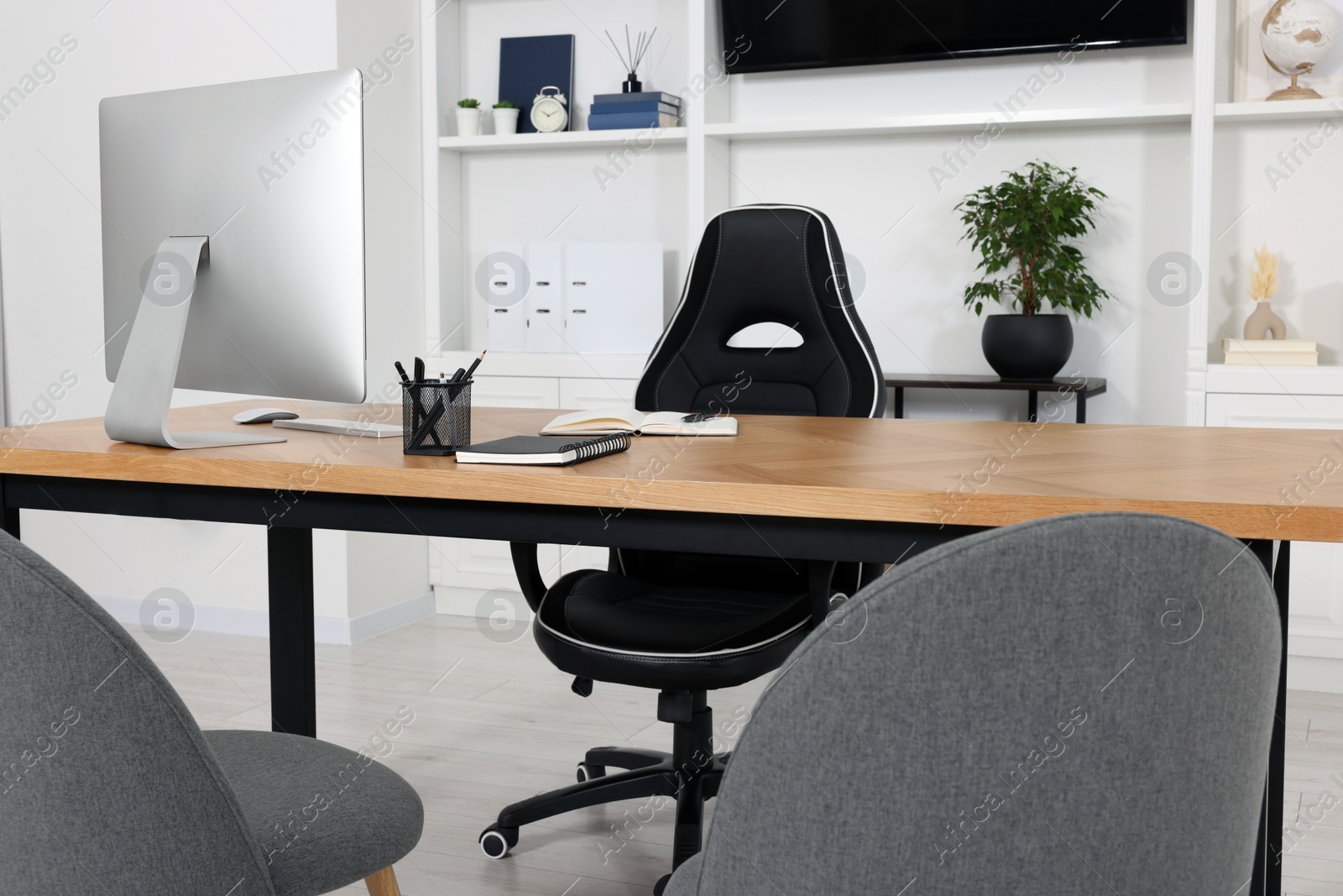 Photo of Stylish director's workspace with computer and stationery on desk in office. Interior design