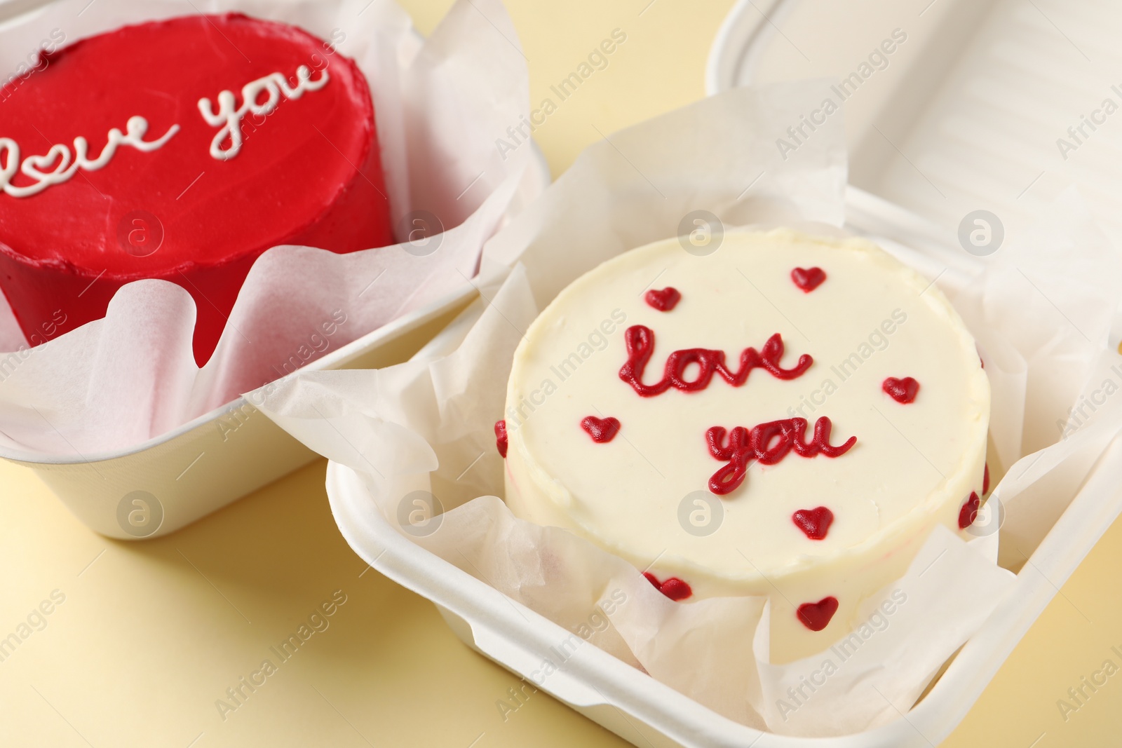 Photo of Bento cakes in takeaway boxes on beige table, closeup. St. Valentine's day surprise