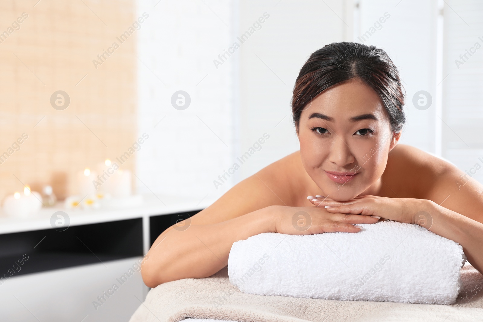 Photo of Beautiful Asian woman lying on massage table in spa salon. Space for text