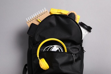 Photo of Stylish urban backpack with different items on grey background, top view