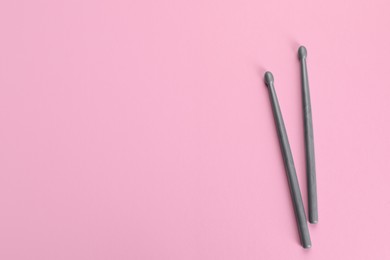 Two grey drumsticks on pink background, top view. Space for text