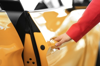 Photo of Young woman opening door of new car, closeup