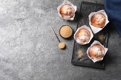 Delicious muffins and sugar on grey table, flat lay. Space for text