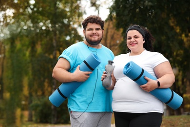 Photo of Overweight couple wearing sportswear with mats in park