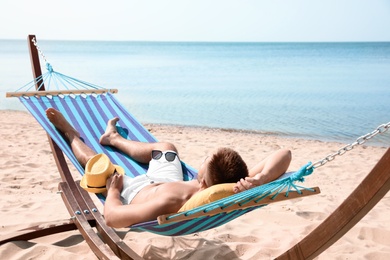 Young man relaxing in hammock on beach