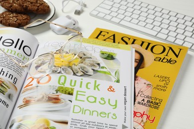 Workplace with modern magazines on white table, closeup