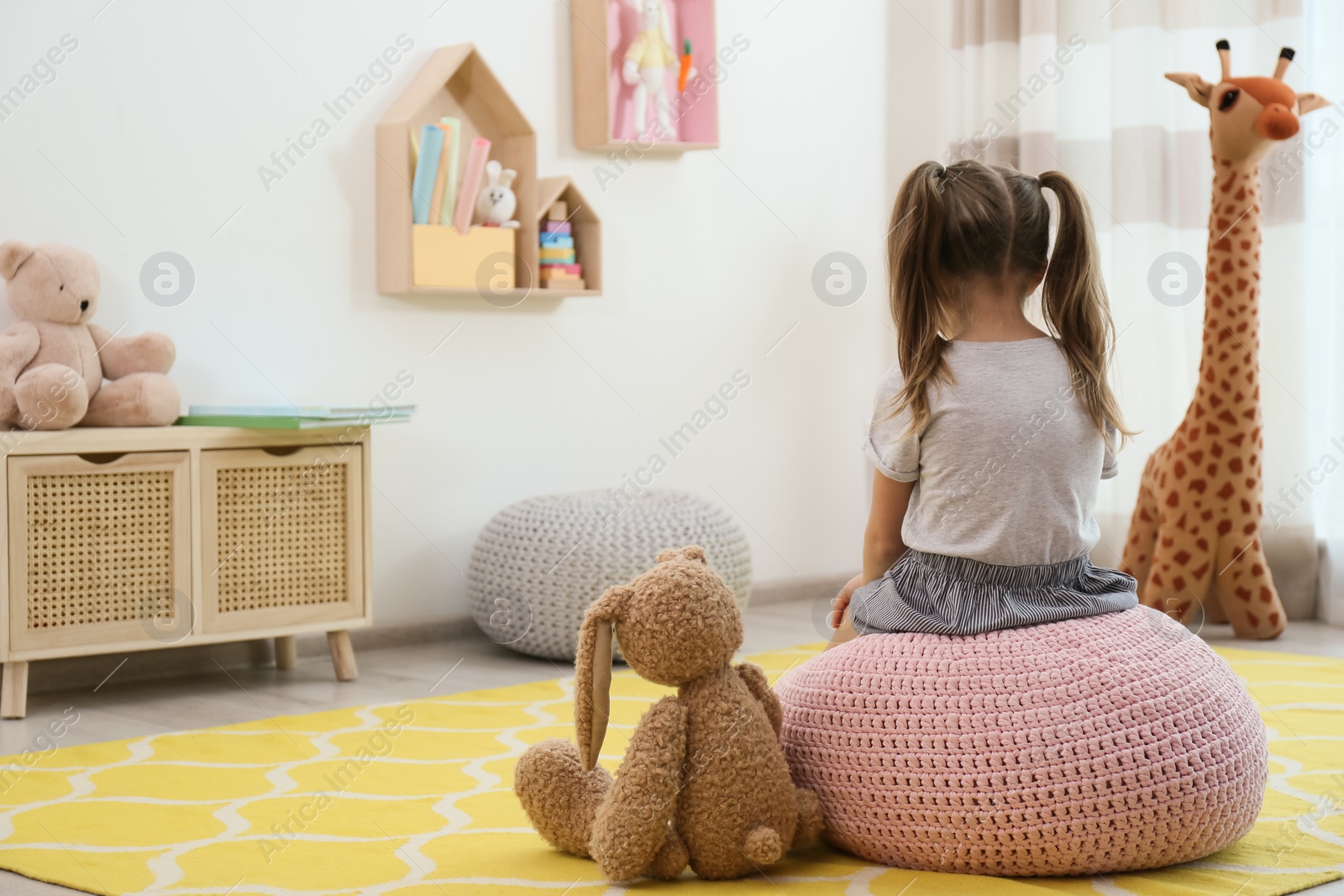 Photo of Lonely little girl with toy bunny at home, back view. Autism concept