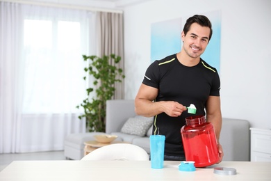 Young athletic man preparing protein shake at home, space for text