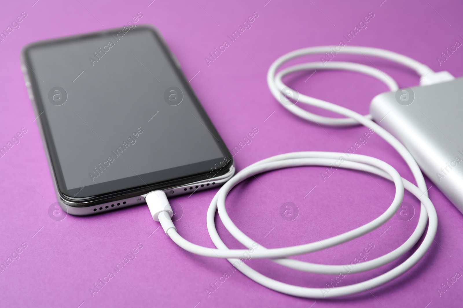 Photo of Smartphone and portable charger on purple background. Modern technology