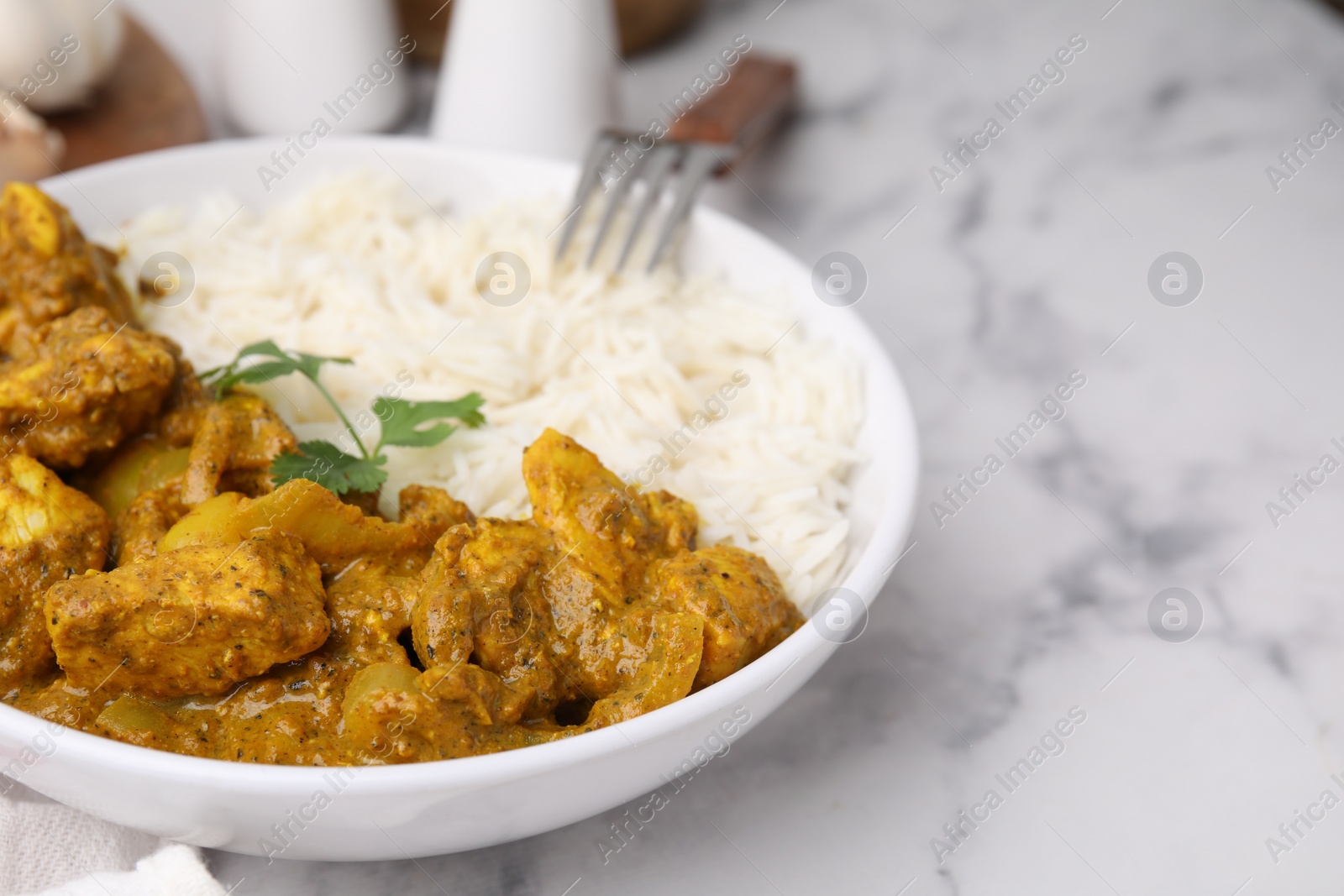 Photo of Delicious chicken curry with rice on white marble table, closeup