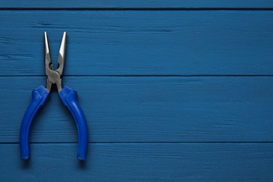 Needle nose pliers on blue wooden table, top view. Space for text