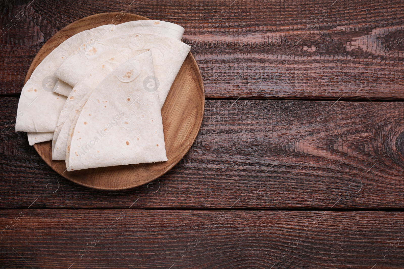 Photo of Delicious folded Armenian lavash on wooden table, top view. Space for text