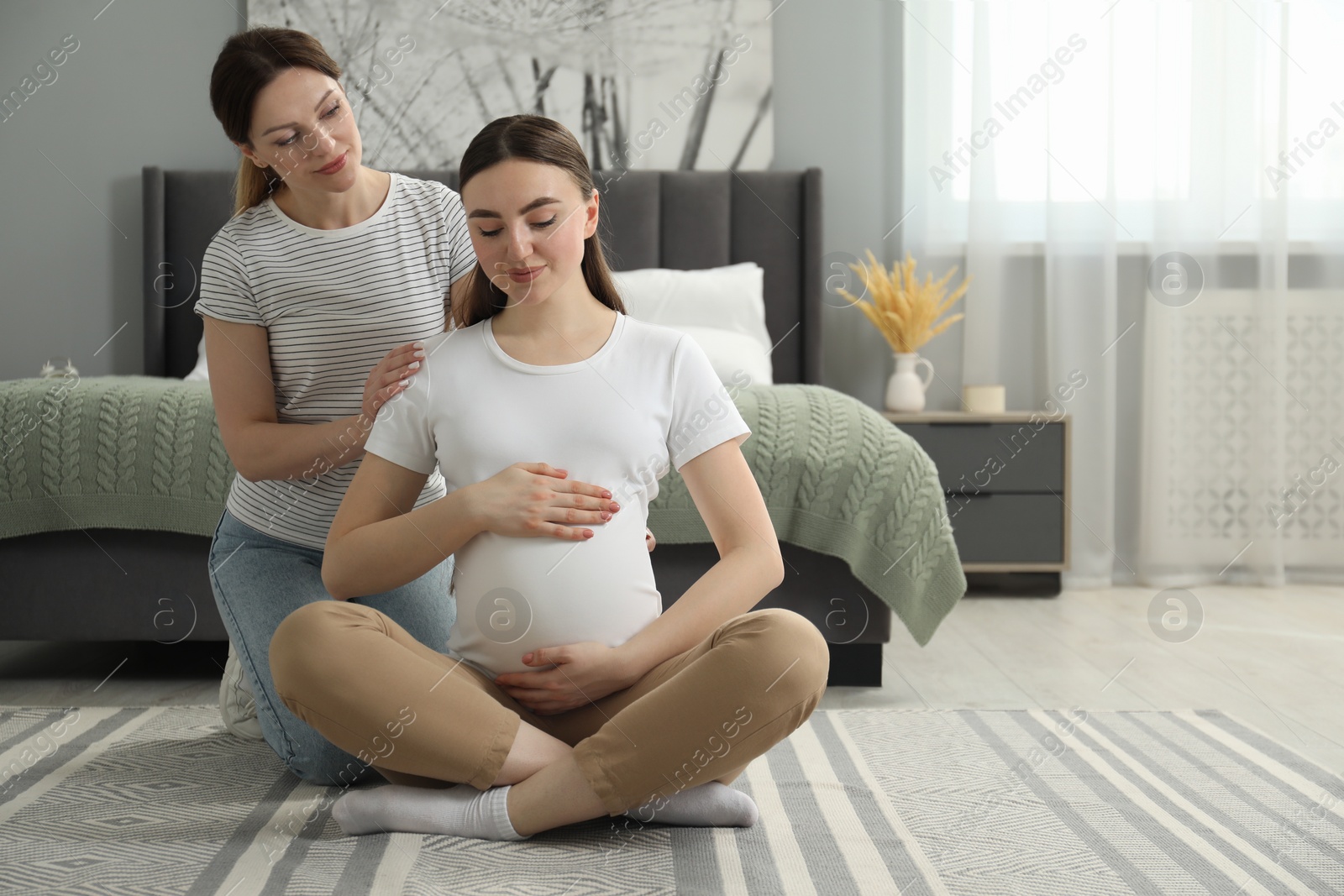 Photo of Doula massaging pregnant woman in bedroom. Preparation for child birth