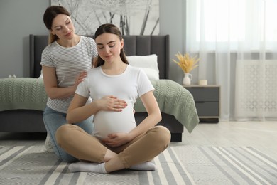 Doula massaging pregnant woman in bedroom. Preparation for child birth