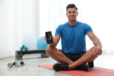 Photo of Man showing smartphone with fitness app indoors. Space for text