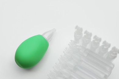 Photo of Single dose ampoules of sterile isotonic sea water solution and nasal aspirator on white background, above view