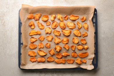 Photo of Baking sheet with sweet potato chips on grey background, top view