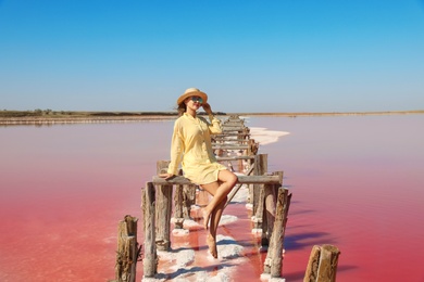 Photo of Beautiful woman with hat posing near pink lake on summer day