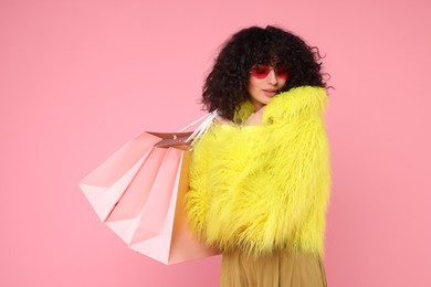 Photo of Happy young woman with shopping bags on pink background