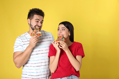 Photo of Emotional couple eating pizza on yellow background