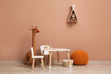 Photo of Cute child room interior with furniture, toys and wigwam shaped shelf on pink wall