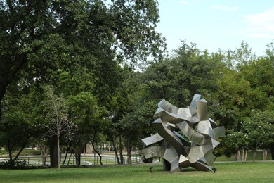 Picturesque view of beautiful park with metal figure on green grass