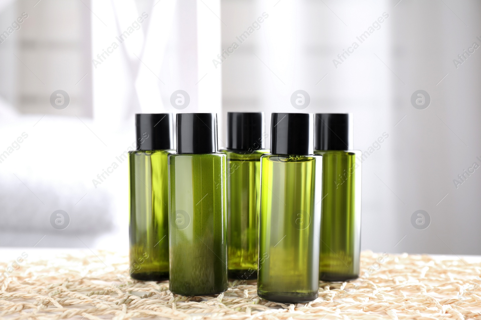 Photo of Mini bottles with cosmetic products on wicker mat indoors