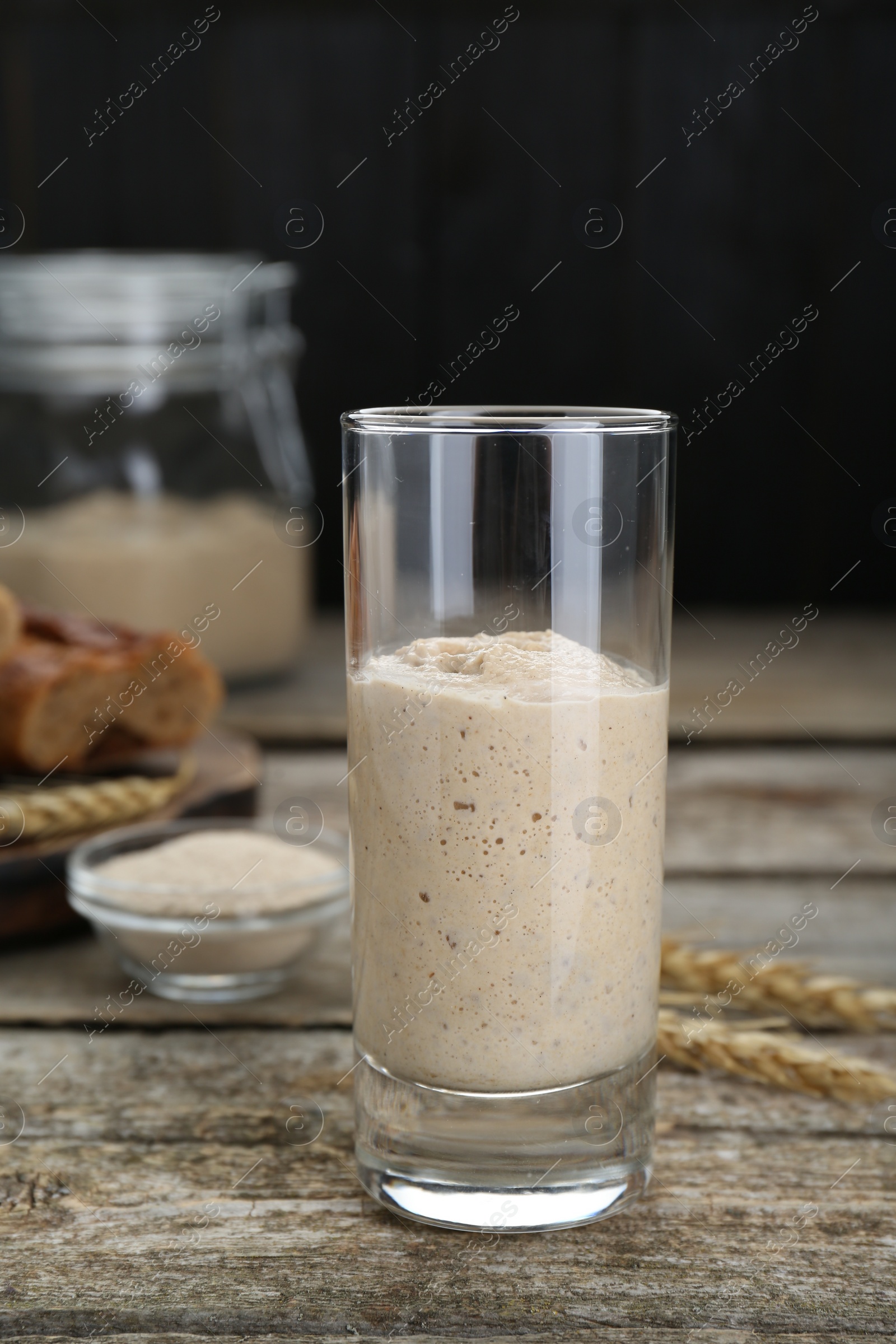 Photo of Glass with fresh sourdough on wooden table