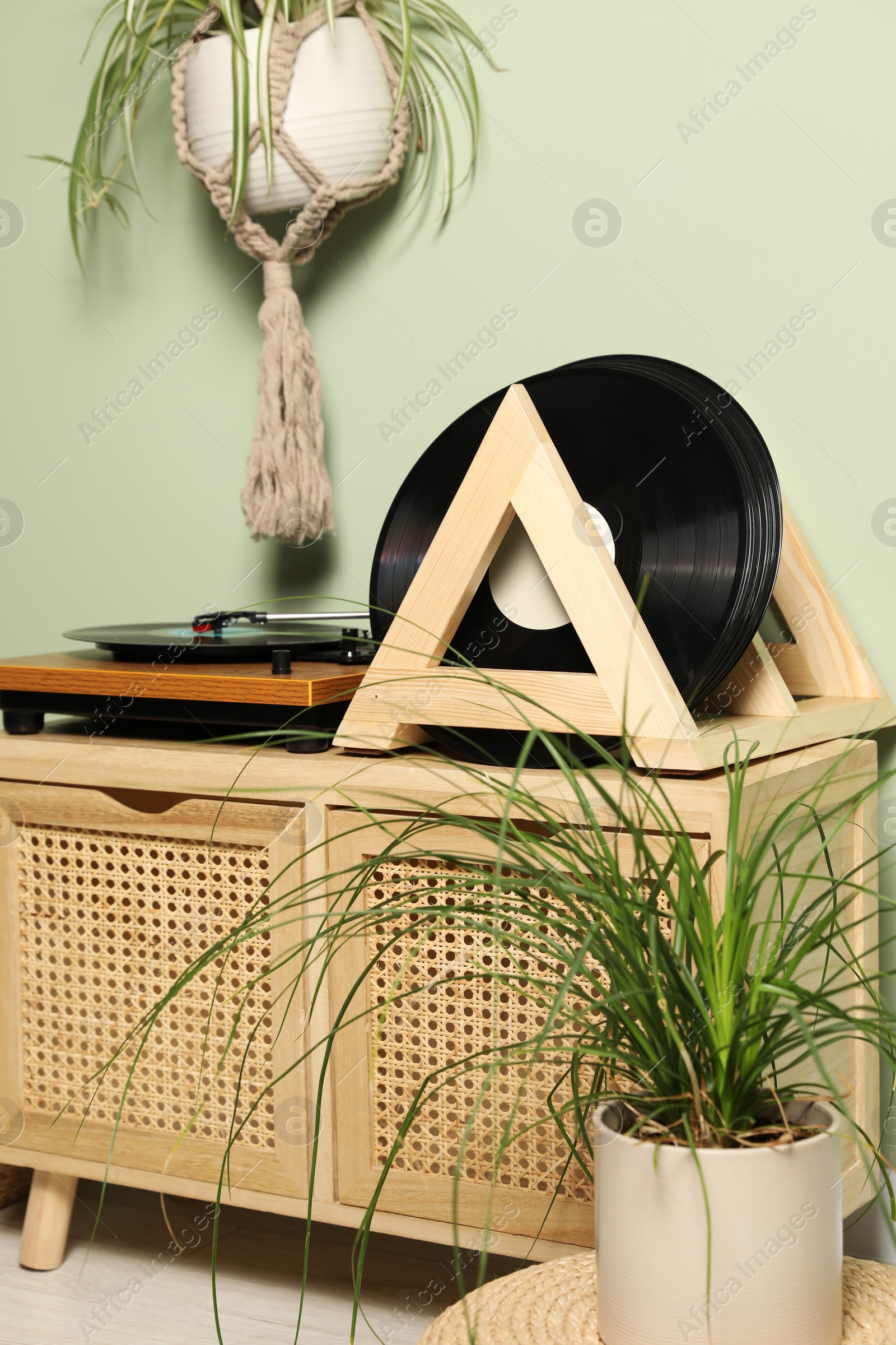 Photo of Vinyl records and player on wooden cabinet near light green wall