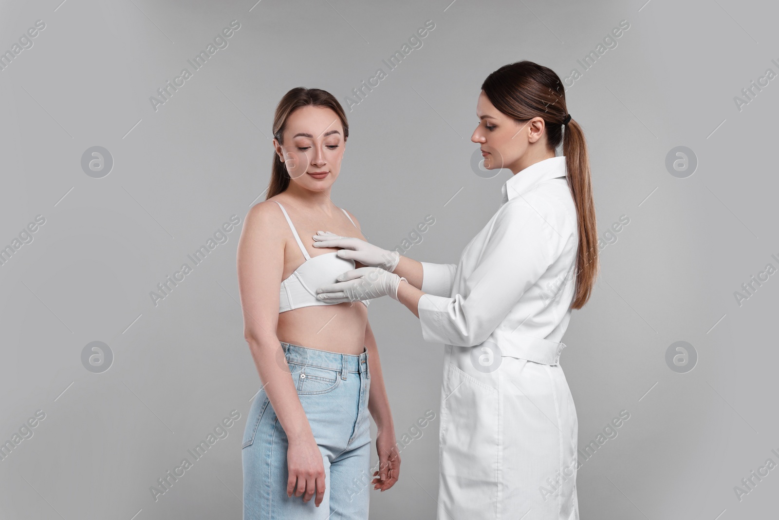 Photo of Mammologist checking woman's breast on gray background