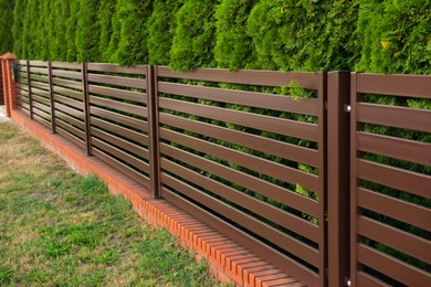 Photo of Beautiful fence with brick and brown iron railing