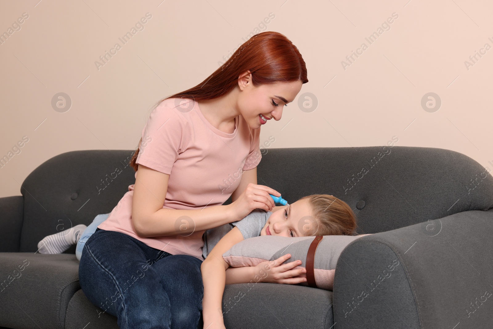 Photo of Mother dripping medication into daughter's ear in living room