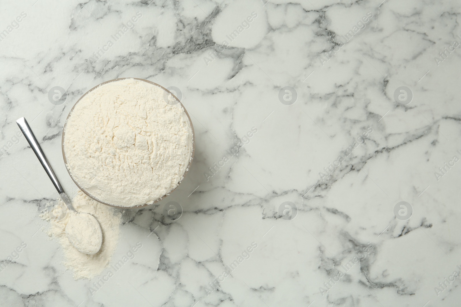 Photo of Ceramic bowl with flour on white marble table, flat lay and space for text. Cooking utensils