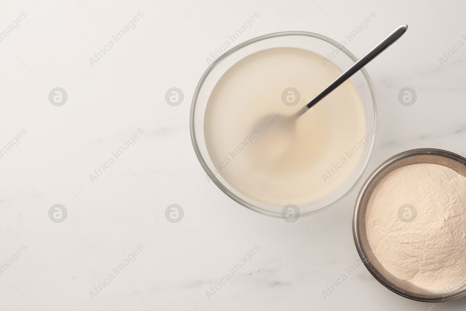 Photo of Agar-agar jelly and powder on white marble table, flat lay. Space for text