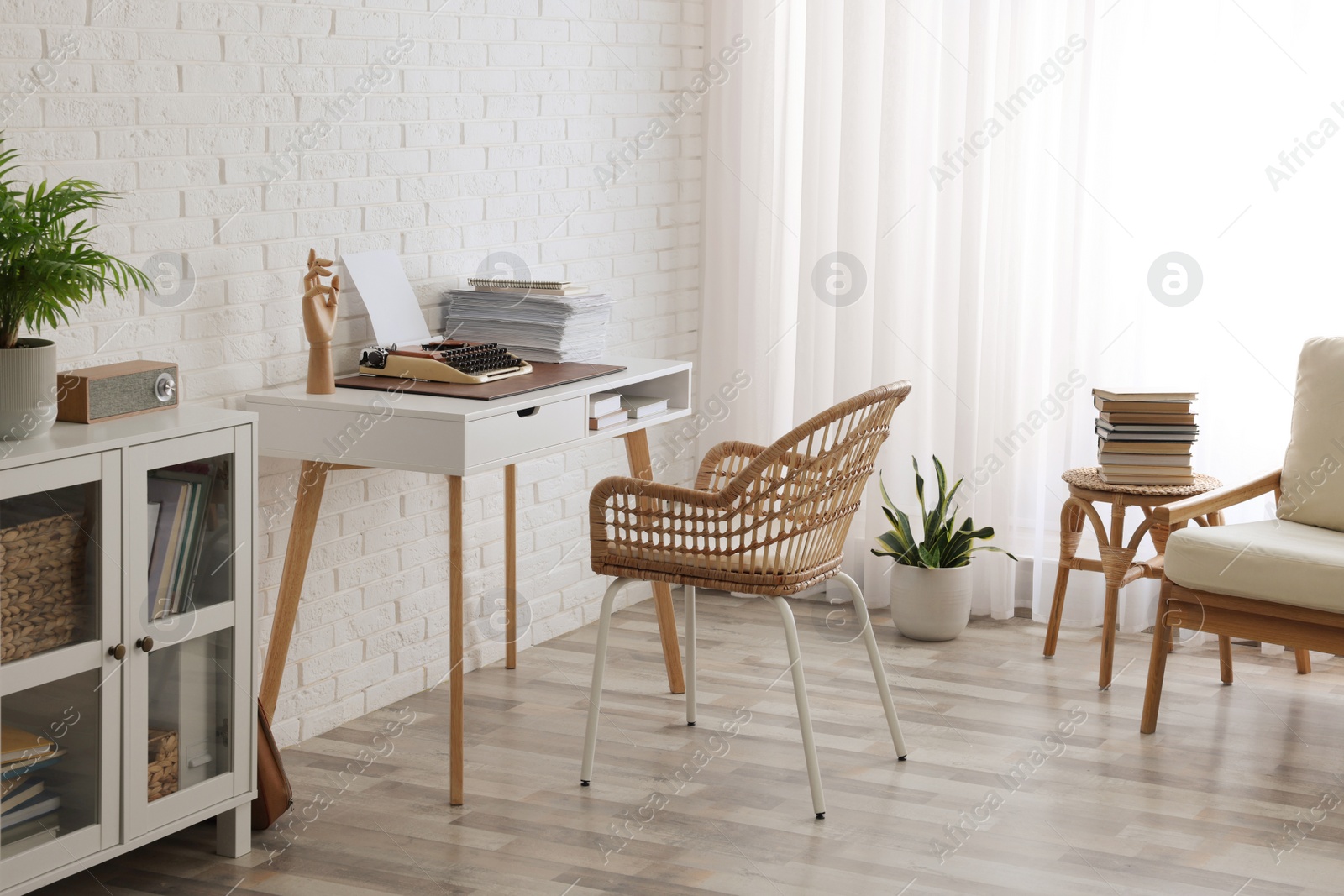 Photo of Comfortable writer's workplace interior with typewriter on desk near white brick wall