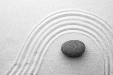 Grey stone on sand with pattern, top view. Zen, meditation, harmony