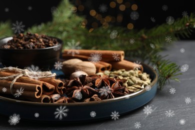 Different spices and fir tree branches on dark table, closeup. Cinnamon, cloves, anise, cardamom, nutmegs