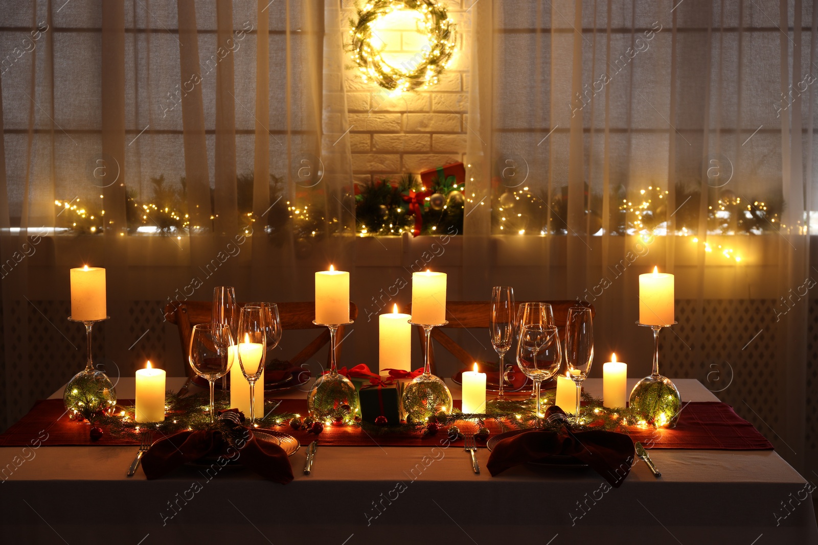 Photo of Christmas table setting with burning candles and festive decor