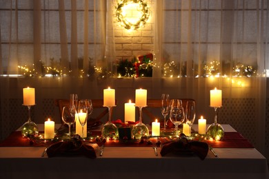 Christmas table setting with burning candles and festive decor