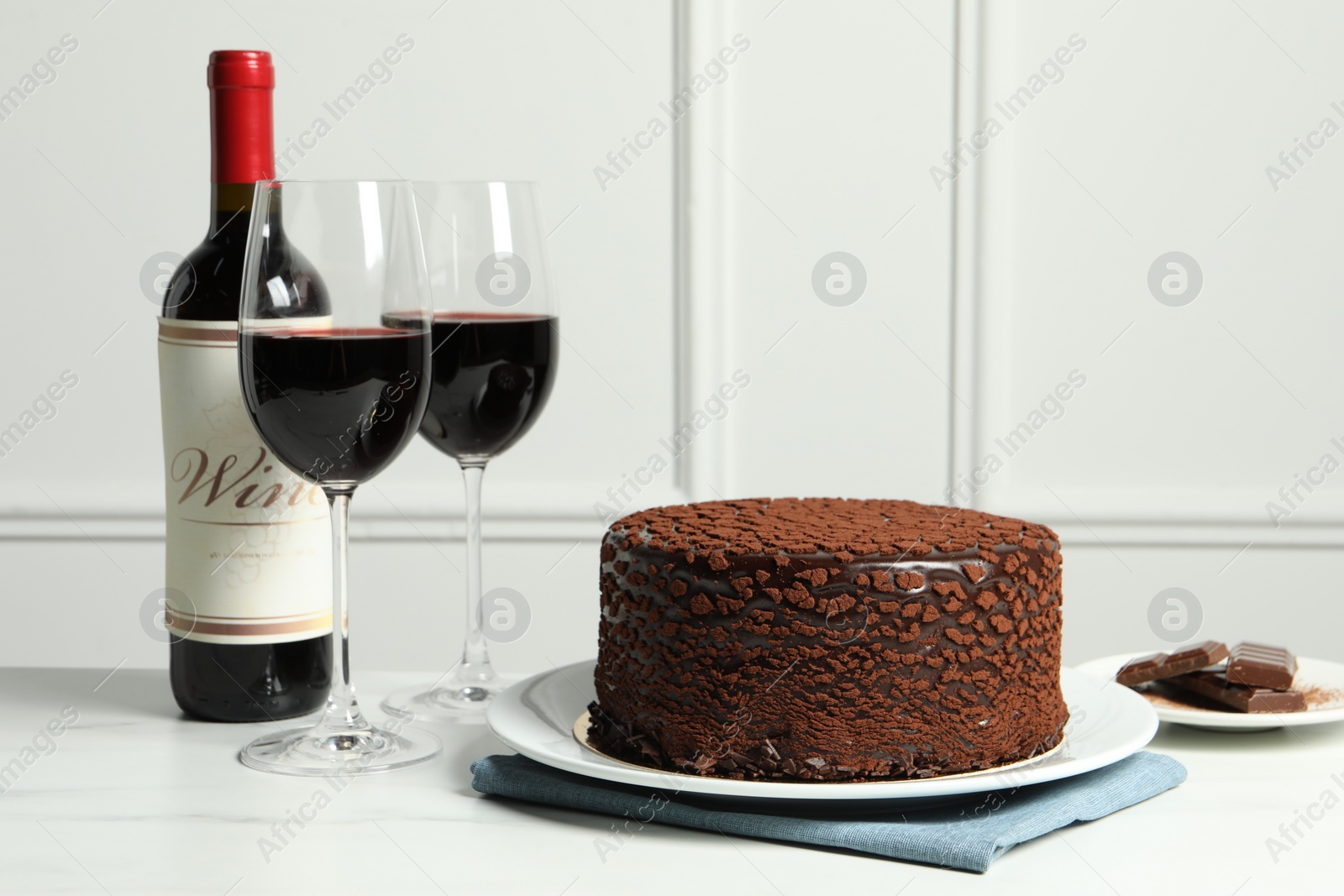 Photo of Delicious chocolate truffle cake and red wine on white marble table