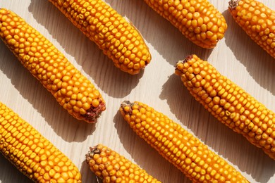 Delicious ripe corn cobs on white wooden table, flat lay