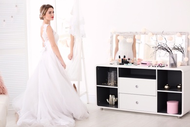 Photo of Beautiful young bride in white wedding dress with makeup created by professional artist indoors